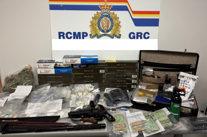 A number of items are displayed on a table including weapons, drugs, cash and contraband tobacco.