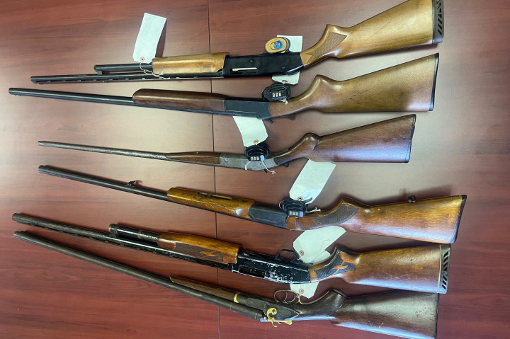 A number of long guns are displayed on a table.