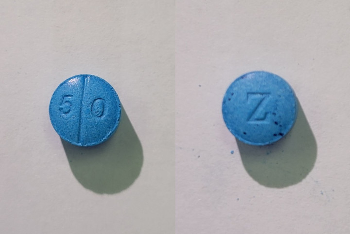 A blue suspected fentanyl pill. One side is etched with 