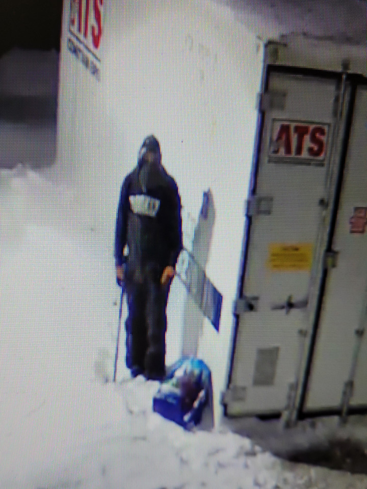 Security camera footage of a suspect wearing dark clothing and a hoodie with white lettering.