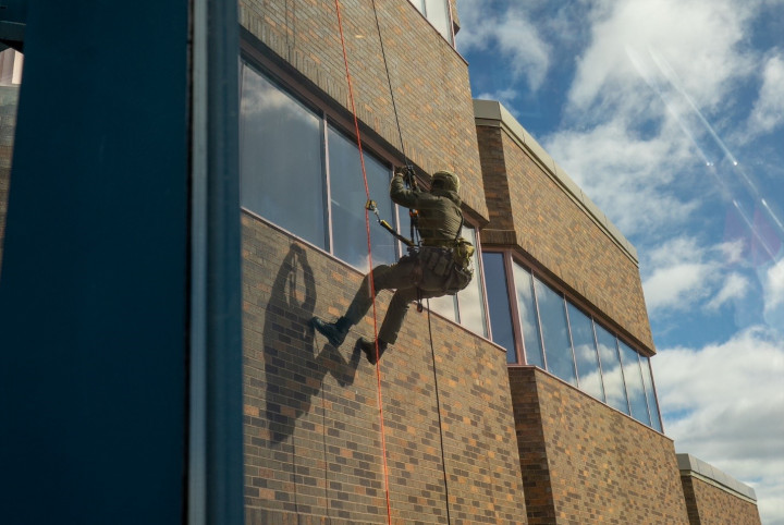 Un policier qui descend en rappel un mur de l'immeuble. 