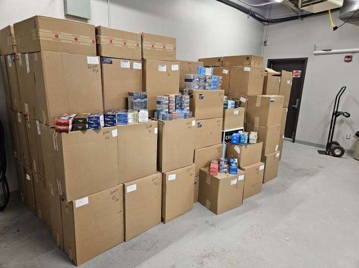 A large quantity of cases of contraband tobacco are displayed inside a facility.