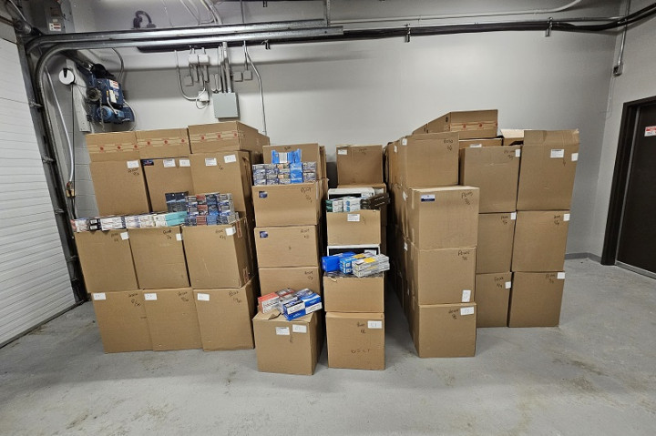 A large quantity of cases of contraband tobacco are displayed inside a facility.