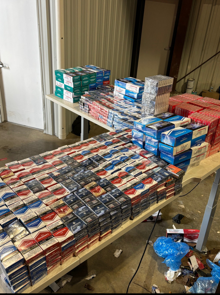 Packs and cartons of cigarettes stacked and displayed on tables.