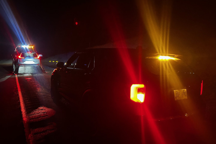 A car being towed with a police car behind it.