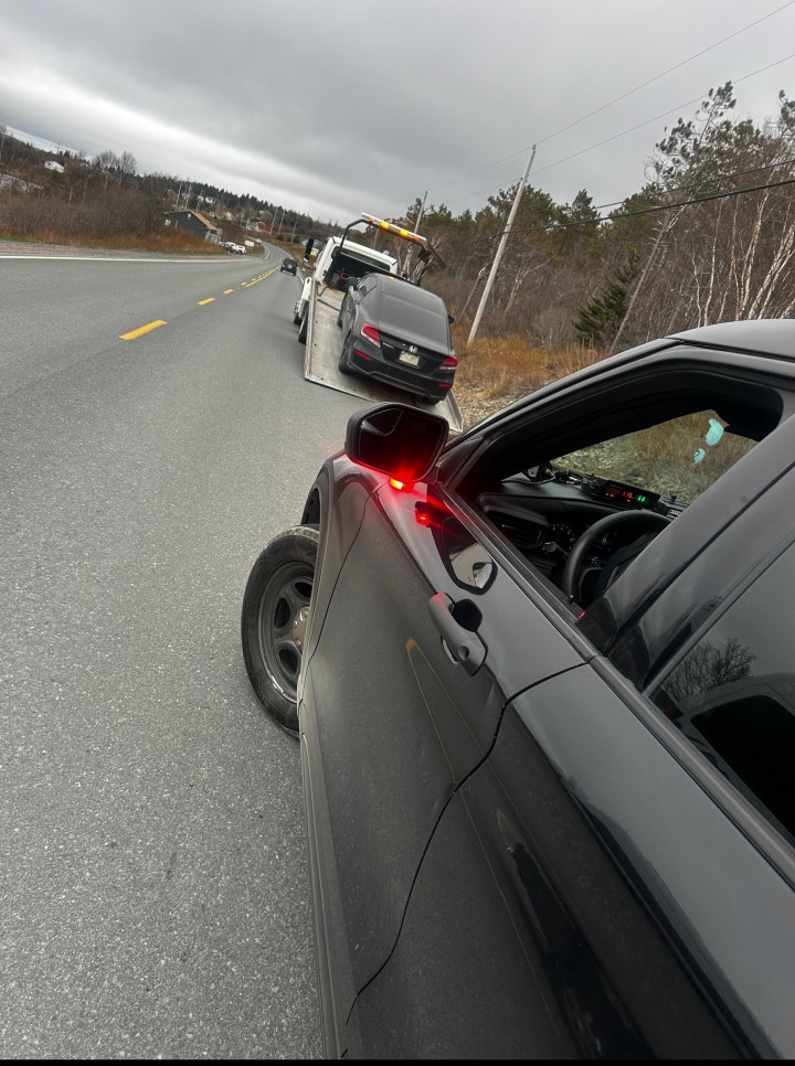 A car being towed with a police car behind it.