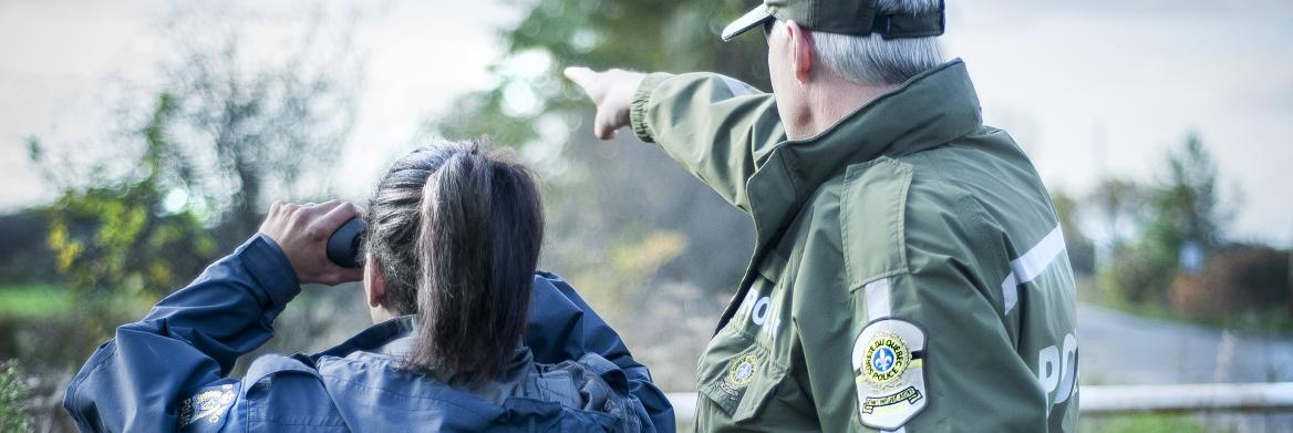 Un homme et une femme de dos regardent un objet qui se trouve à une certaine distance d'eux.