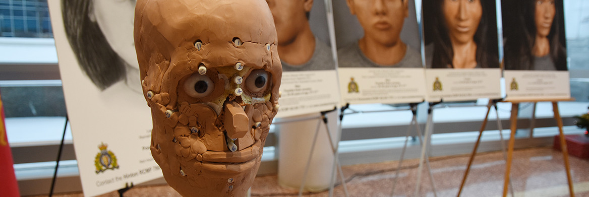 A half-finished facial reconstruction sits in front of five facial sketches.
