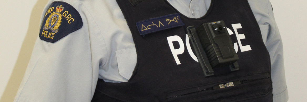 A close up of an RCMP officer at chest level. A body worn camera is attached to their police vest.