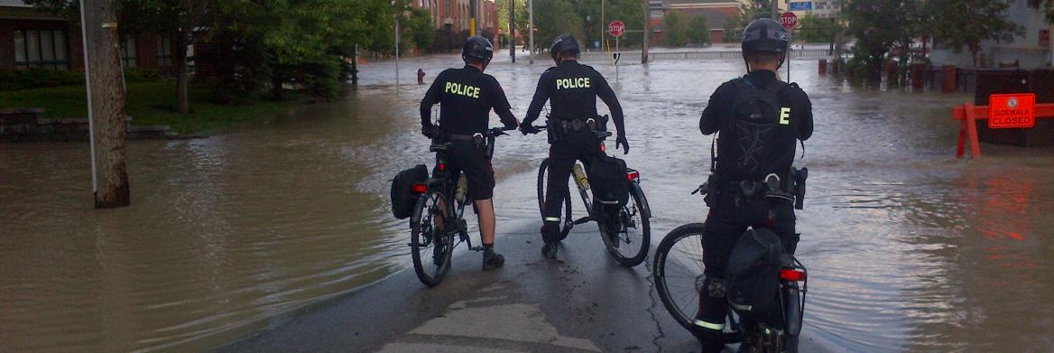Trois policiers à bicyclette près de la zone inondée.