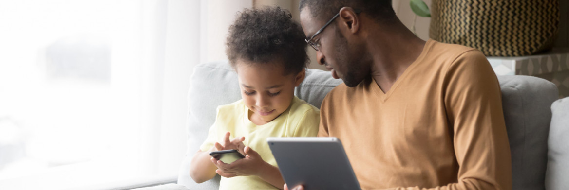 A man and young boy look at a tablet/smartphone.