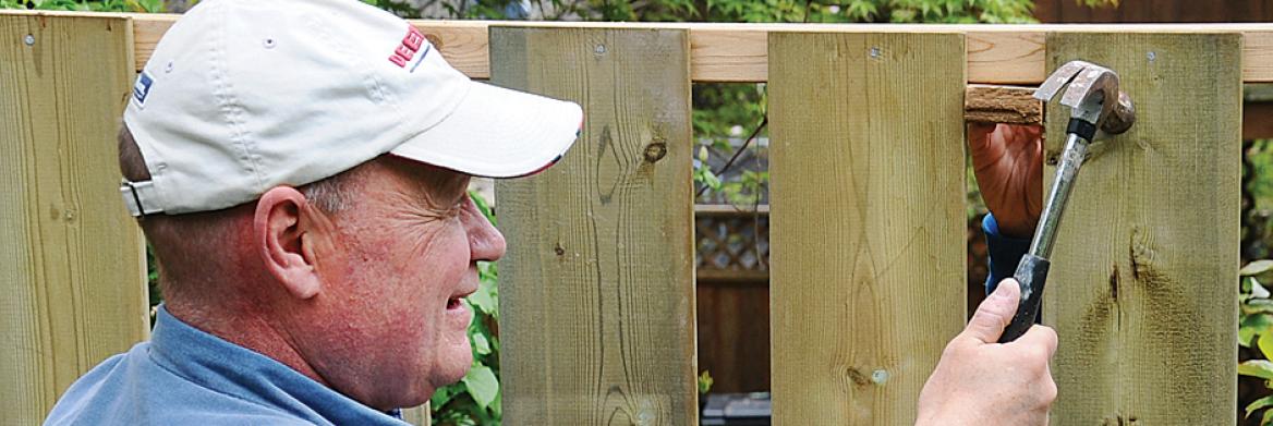 Three people constructing a fence.