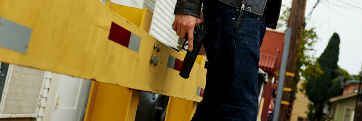 Un homme qui tient une arme de poing dans une ruelle.