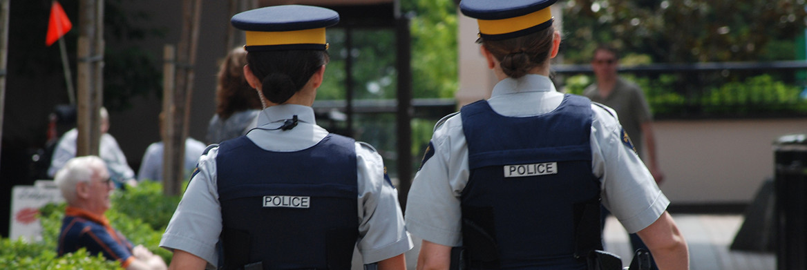 Two female RCMP officers walk side by side on a street.