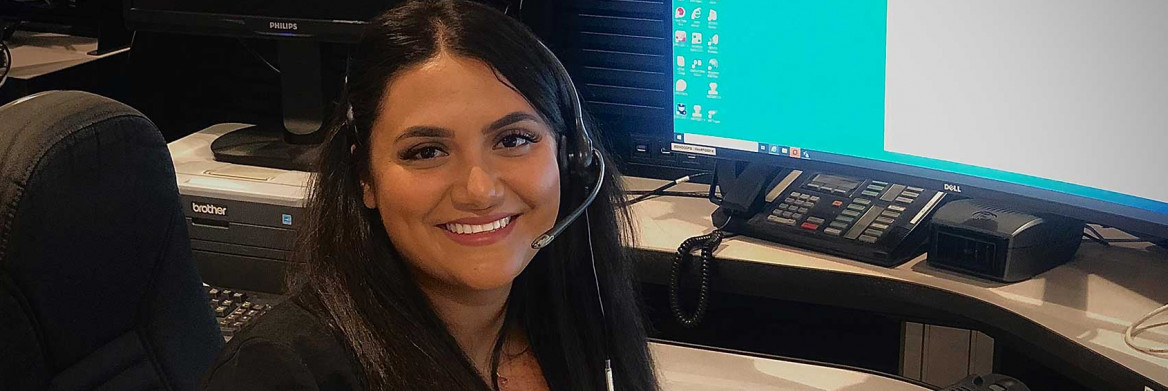 Une femme est assise à un bureau avec un écran d'ordinateur en arrière-plan.