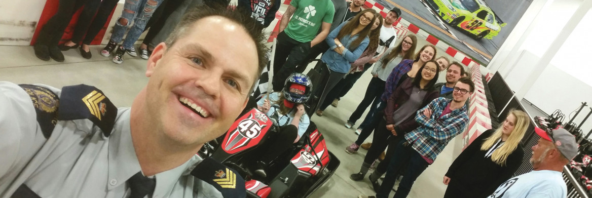 Selfie of RCMP police officer with a group of young people behind him.