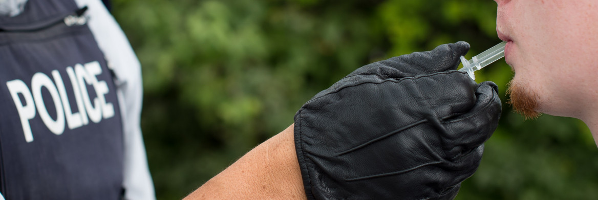 Police officer collects man's saliva in small clear tube.