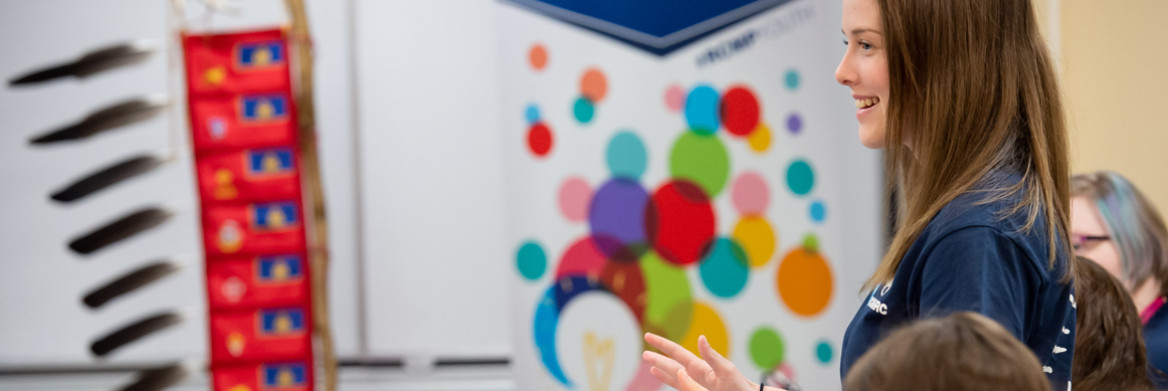 Young woman speaking in a room while gesturing her hands.