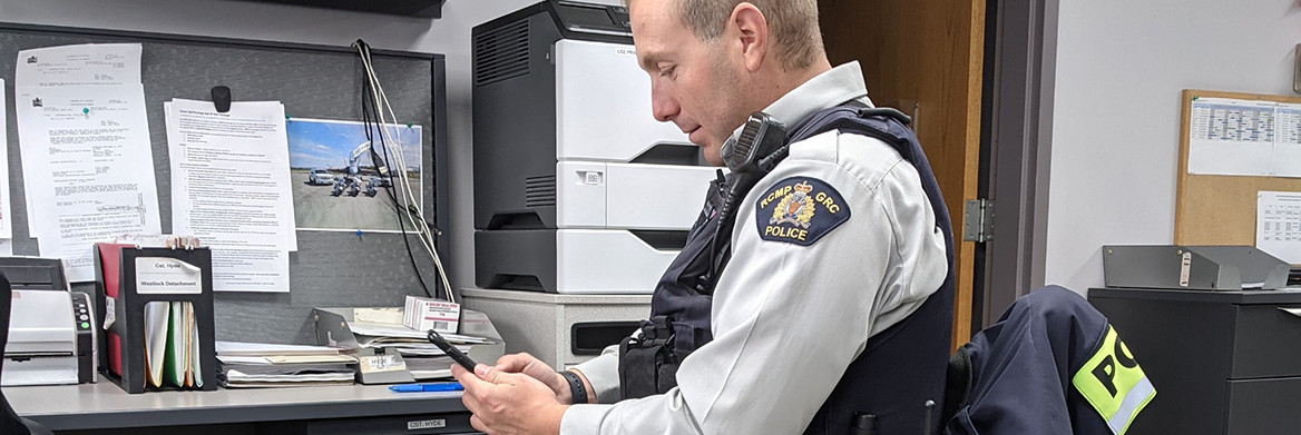 An RCMP member in uniform uses a smart phone.