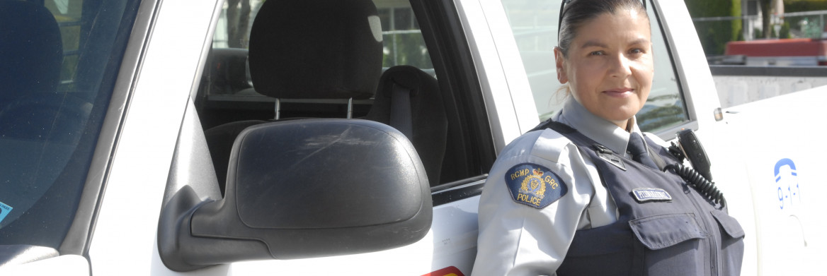 A female RCMP officer standing next to a police vehicle.