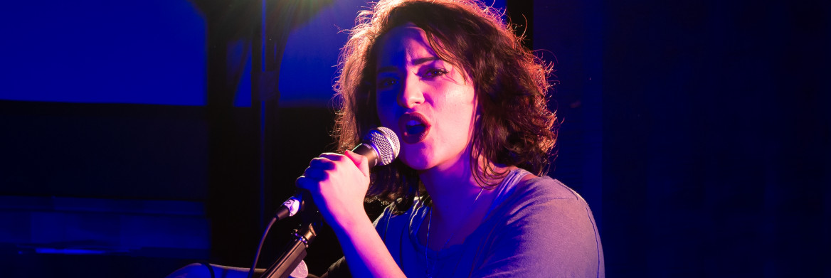Une jeune femme chante dans un microphone.