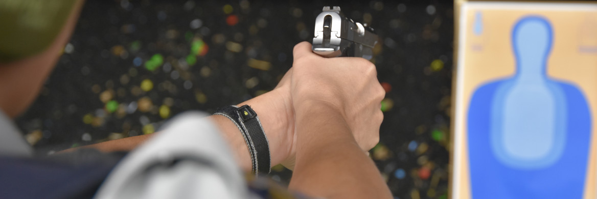 Police officer aiming a firearm at a firing range.