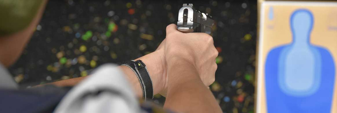 A police officer aims a firearm at a firing range.