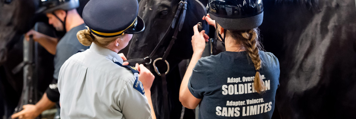 Une membre de la GRC et une femme debout à côté d'un cheval. 