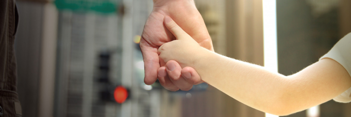 Man holding the hand of a young girl in a city.