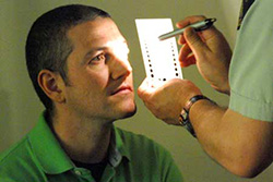 A police officer checks a man's pupil size